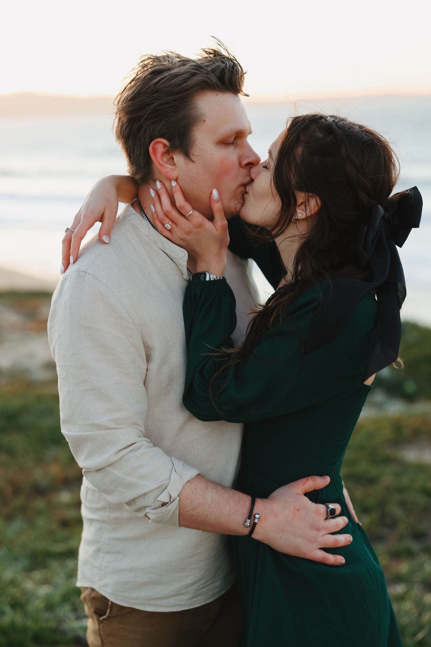 A tender romantic moment shared between a couple at sunset near the ocean.