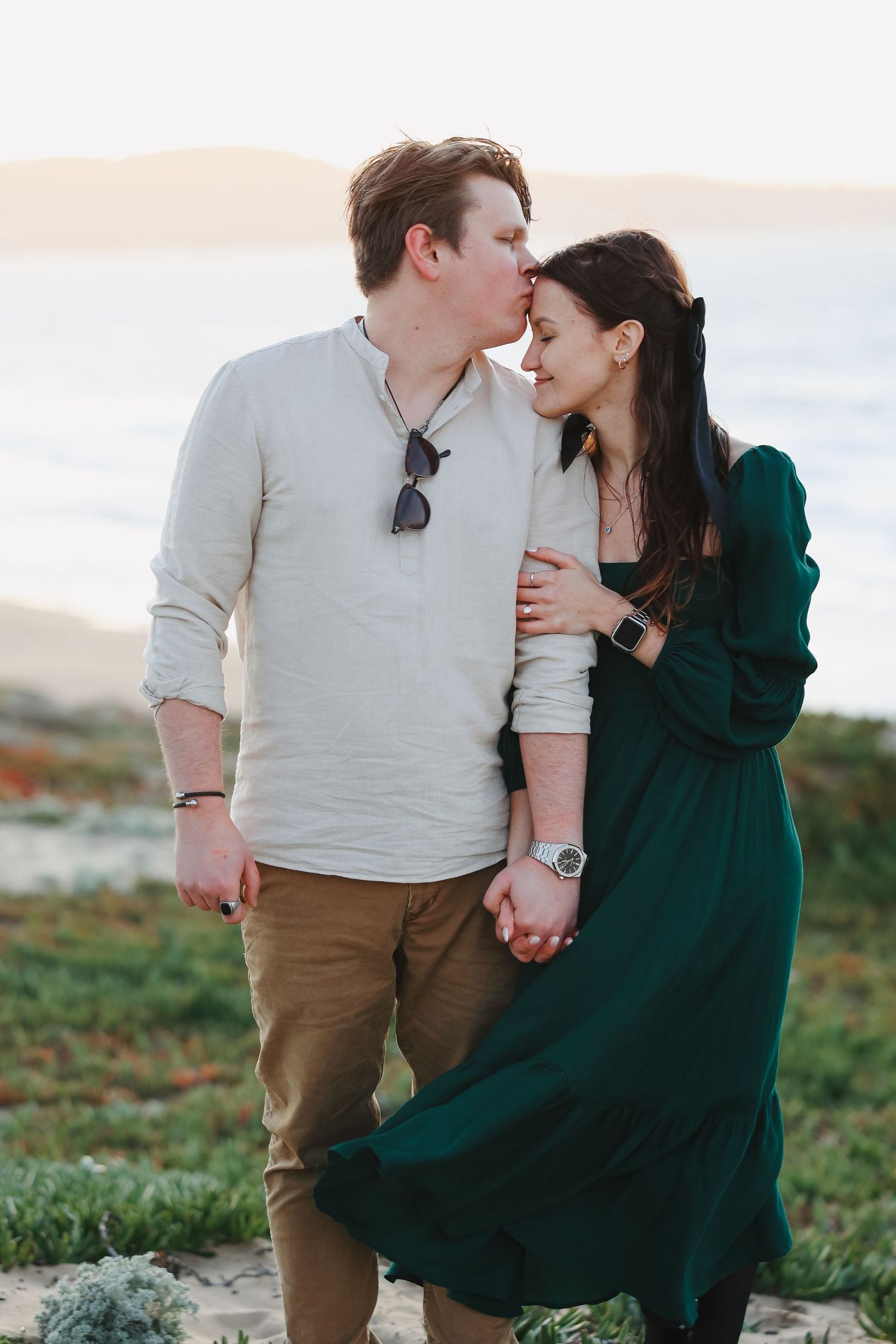 A romantic couple shares an intimate moment while walking along a coastal trail.