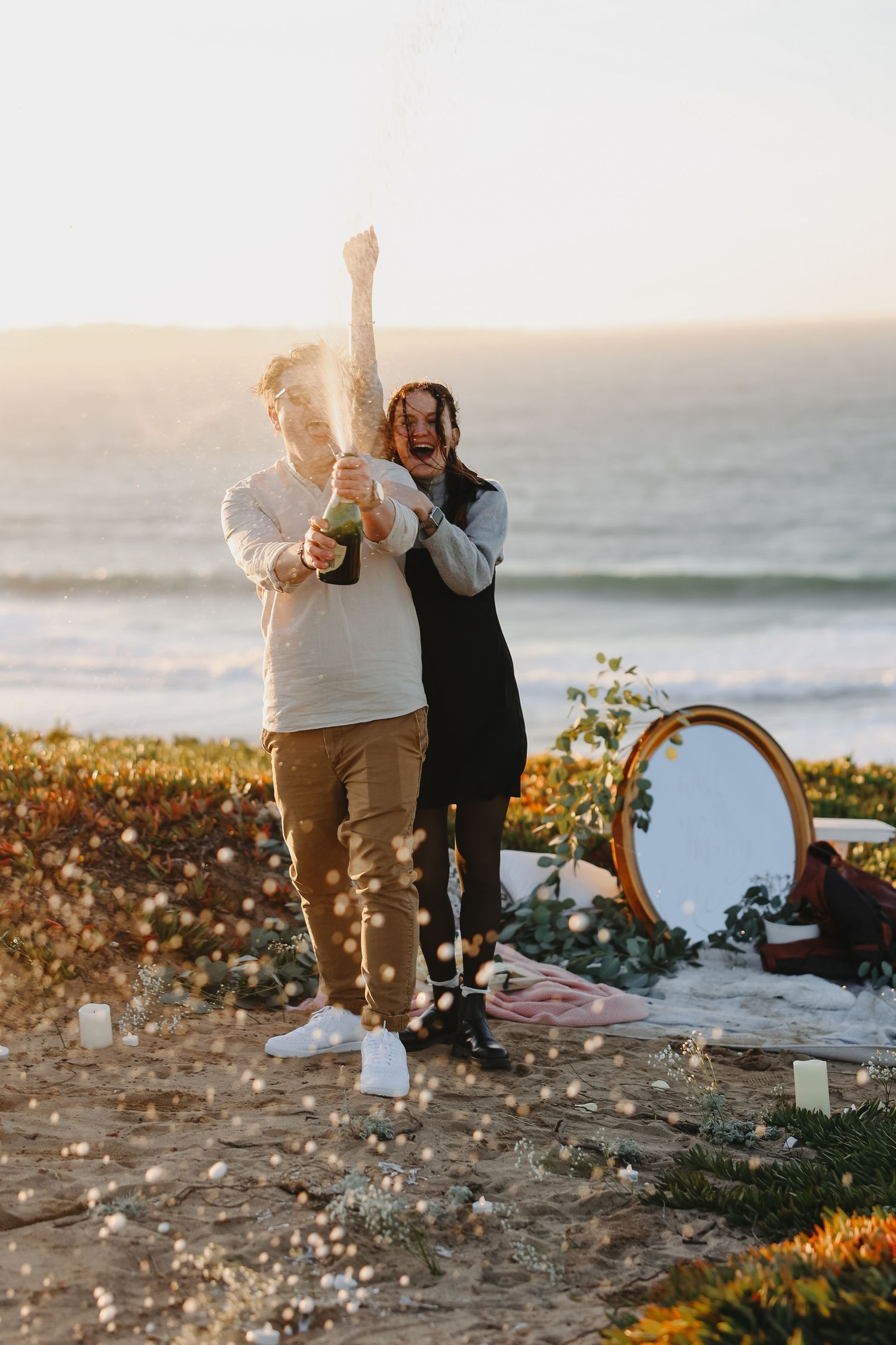 A champagne celebration moment during a coastal proposal with sparkling confetti.