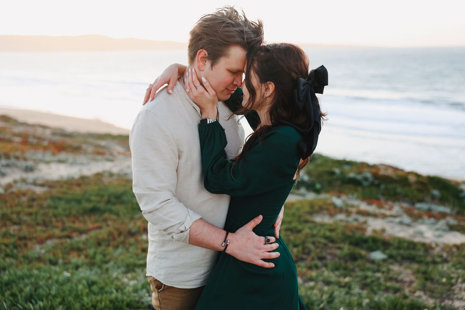 A tender moment between a couple standing on a coastal overlook.