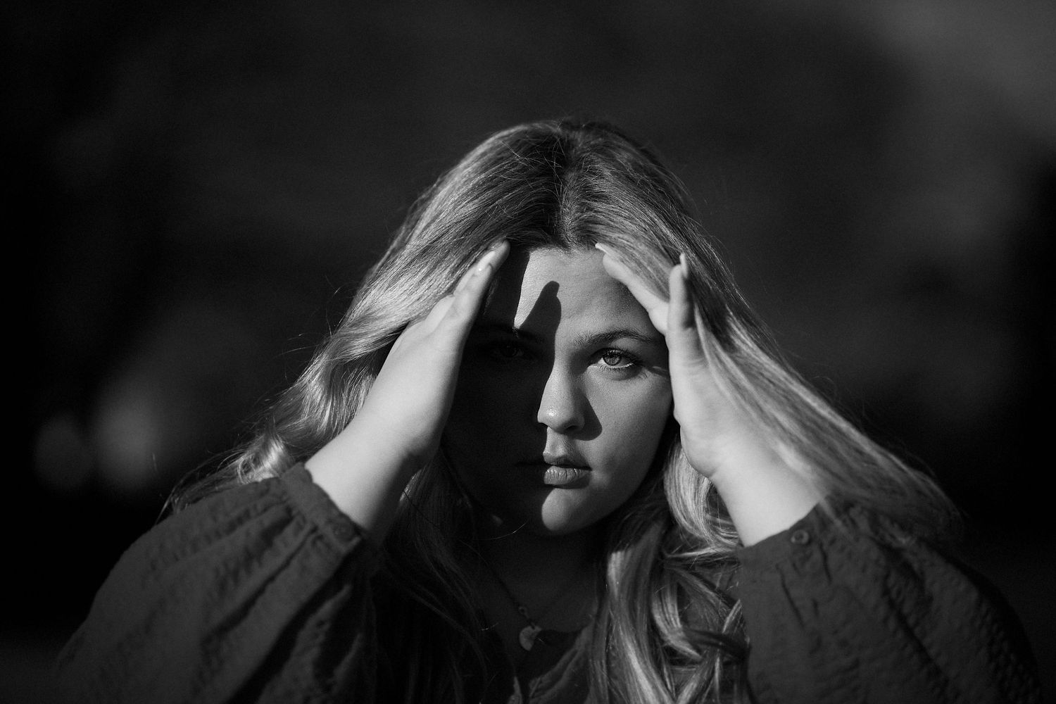 Dramatic black and white portrait showing intense emotion with hands framing face.
