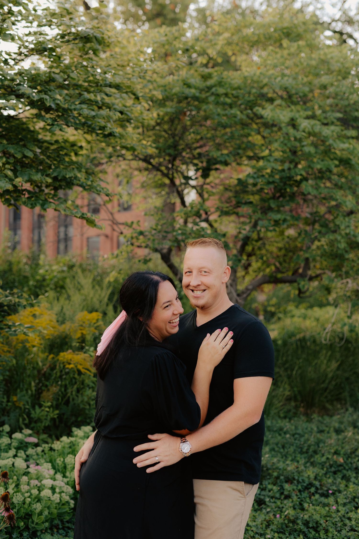 couple posing near the downtown UNL area in Lincoln NE amidst flowers and shrubbery