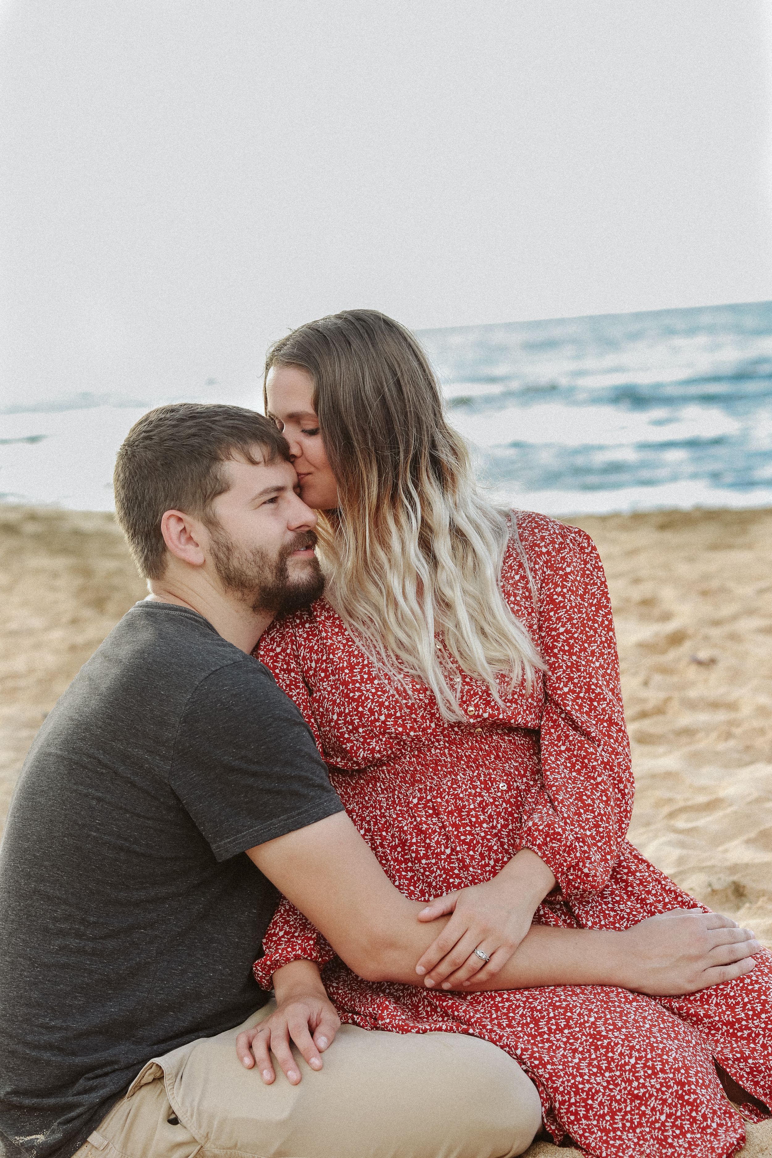 Romantic beach moment captured with ocean waves in background.