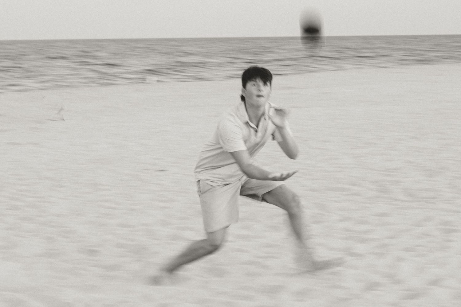 Black and white photo series of people playing and running on beach.