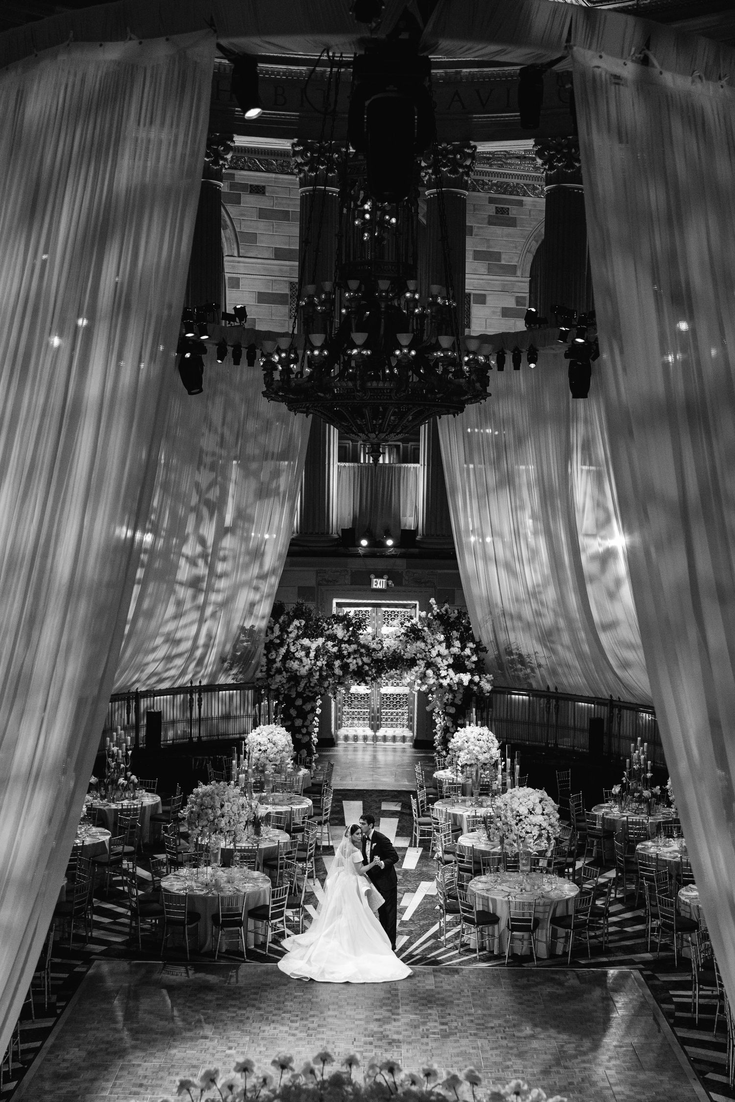 Dramatic overhead view of luxurious wedding reception with chandelier and white draping.