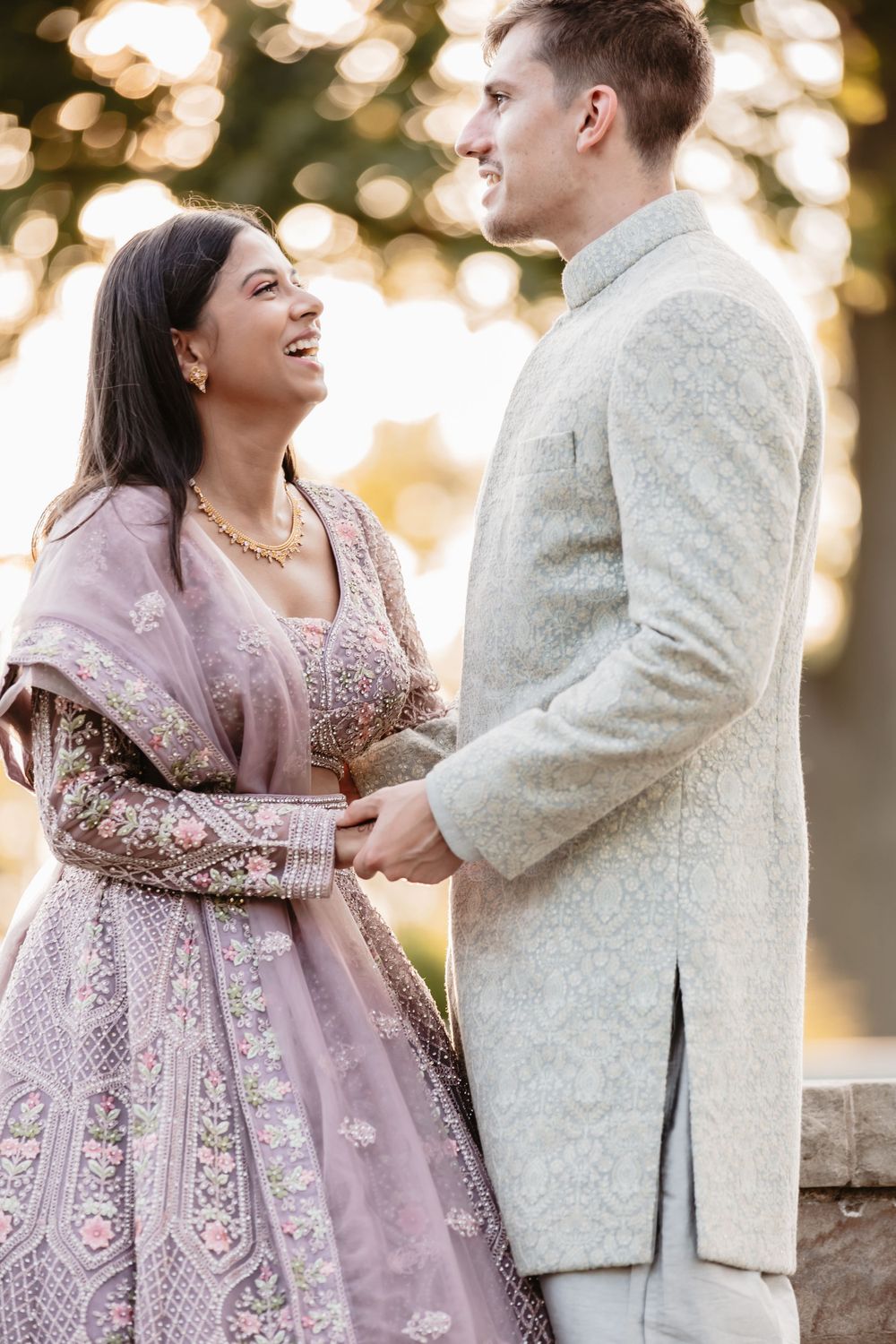 Wedding couple in fusion attire sharing romantic moments at sunset.
