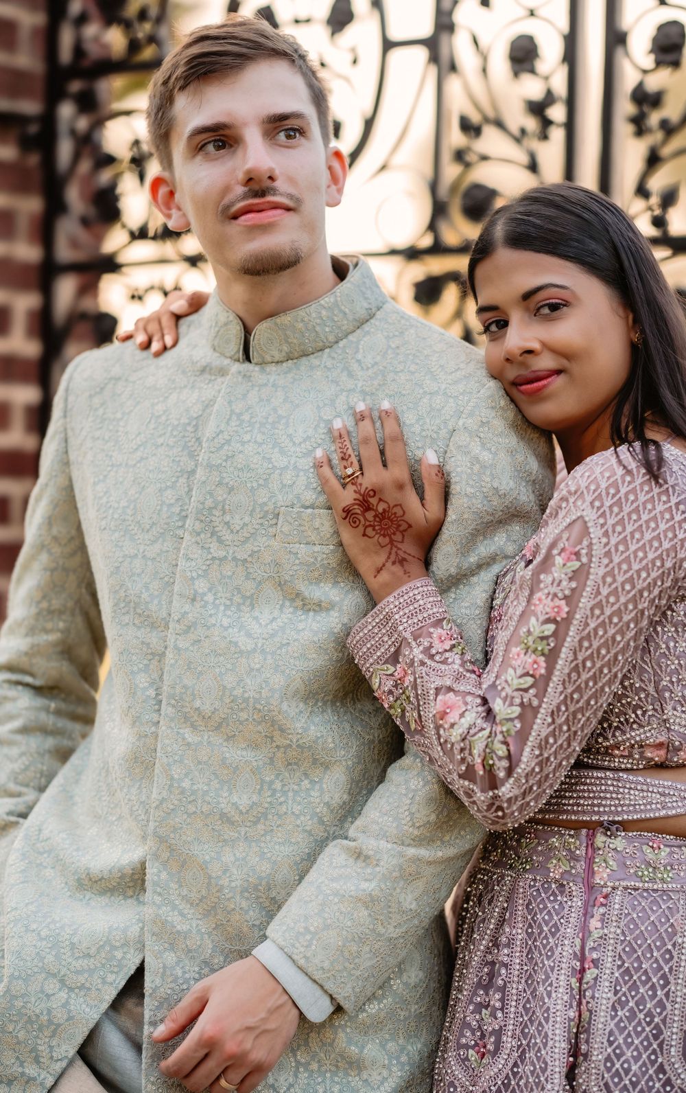 Close-up of newlyweds in fusion wedding attire with intricate henna details.