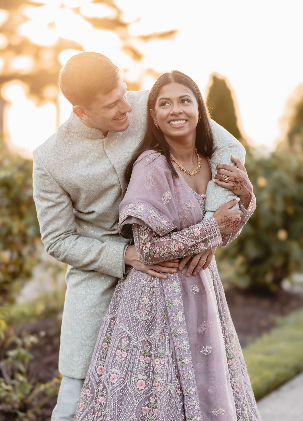 A romantic moment captured in golden sunlight with a couple in formal wear outdoors.