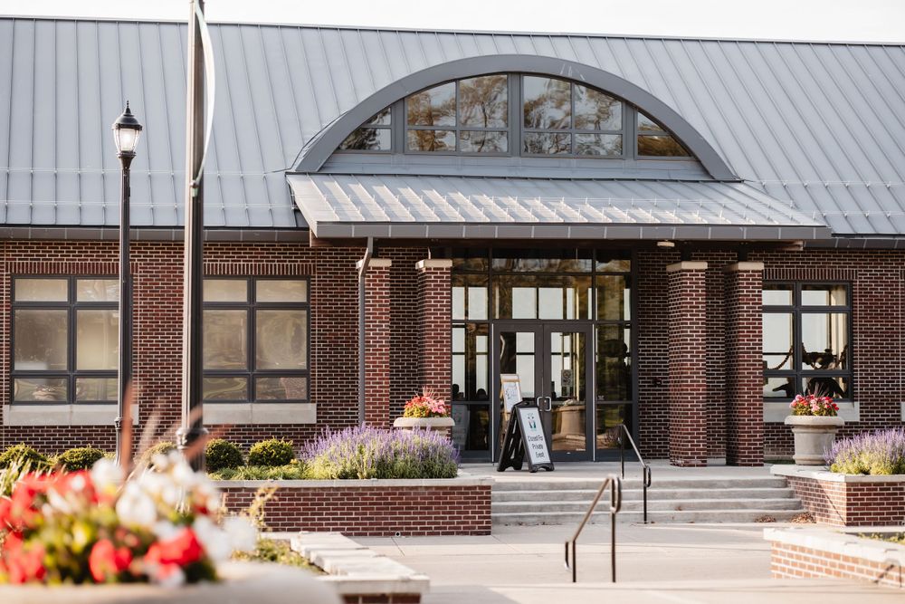 Modern brick building exterior with arched windows and metal roof details.