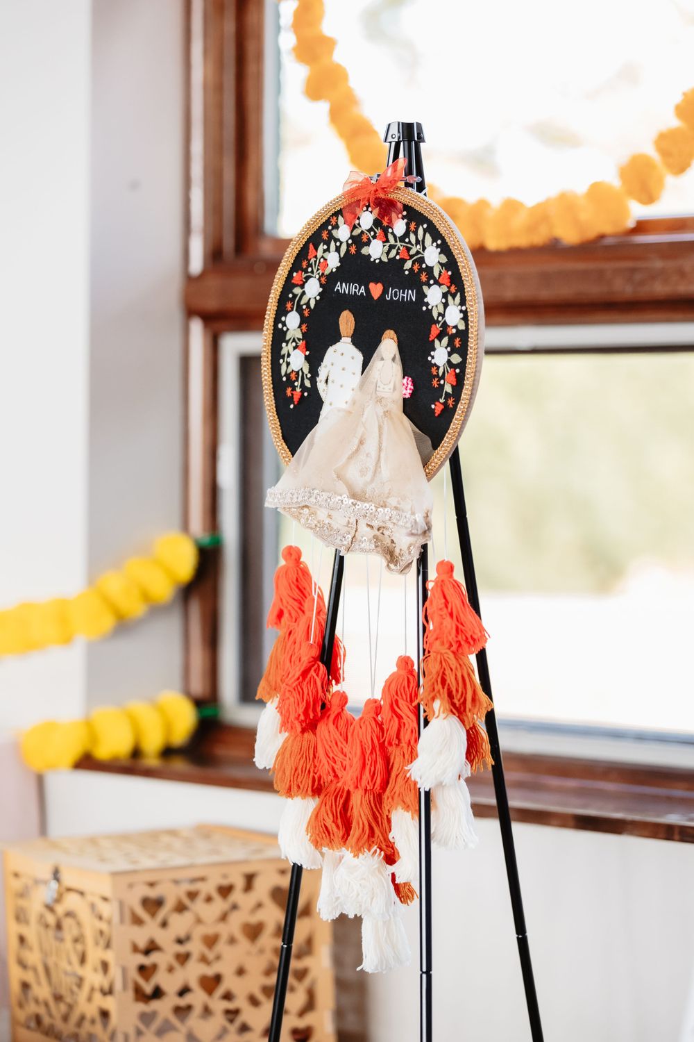 Wedding decorations featuring ornate frames with orange tassels against white walls.
