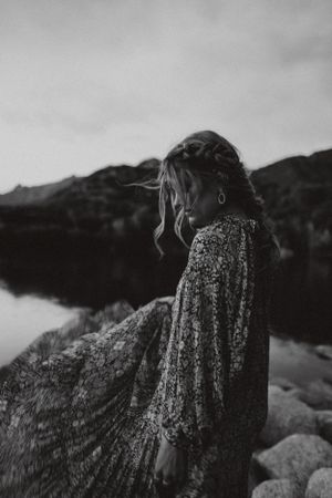 Black and white image of a woman wearing a Free People flowing dress with braided hair by a lake