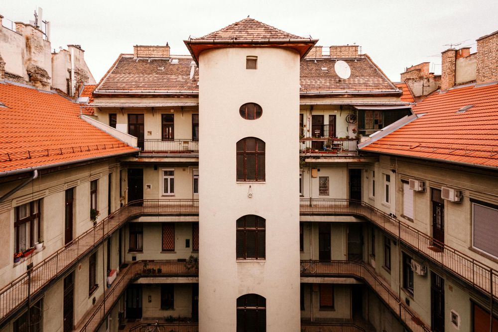 Historic apartment building courtyard with white tower and orange terracotta roofs in European architectural style.