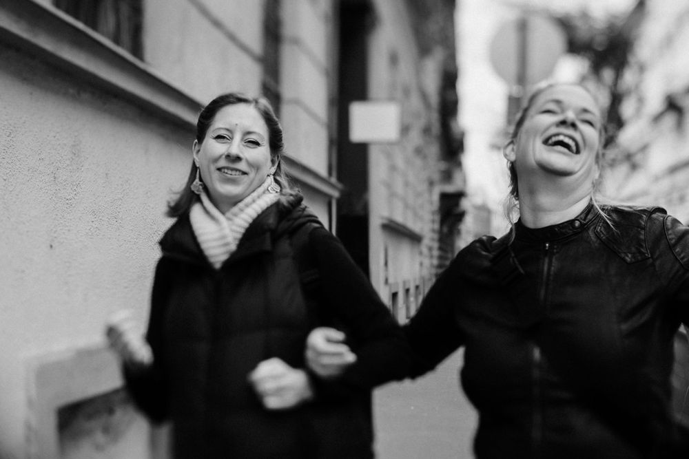 Black and white photo of friends laughing together on city street.
