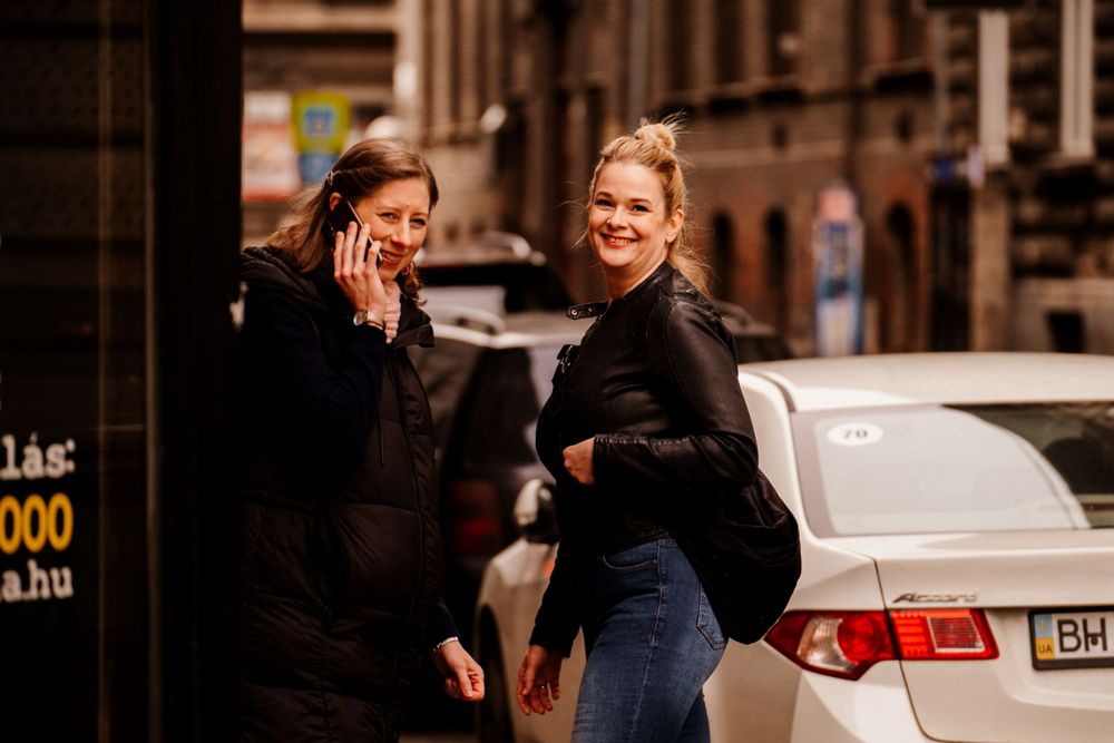 Two women sharing a laugh while walking on urban street.