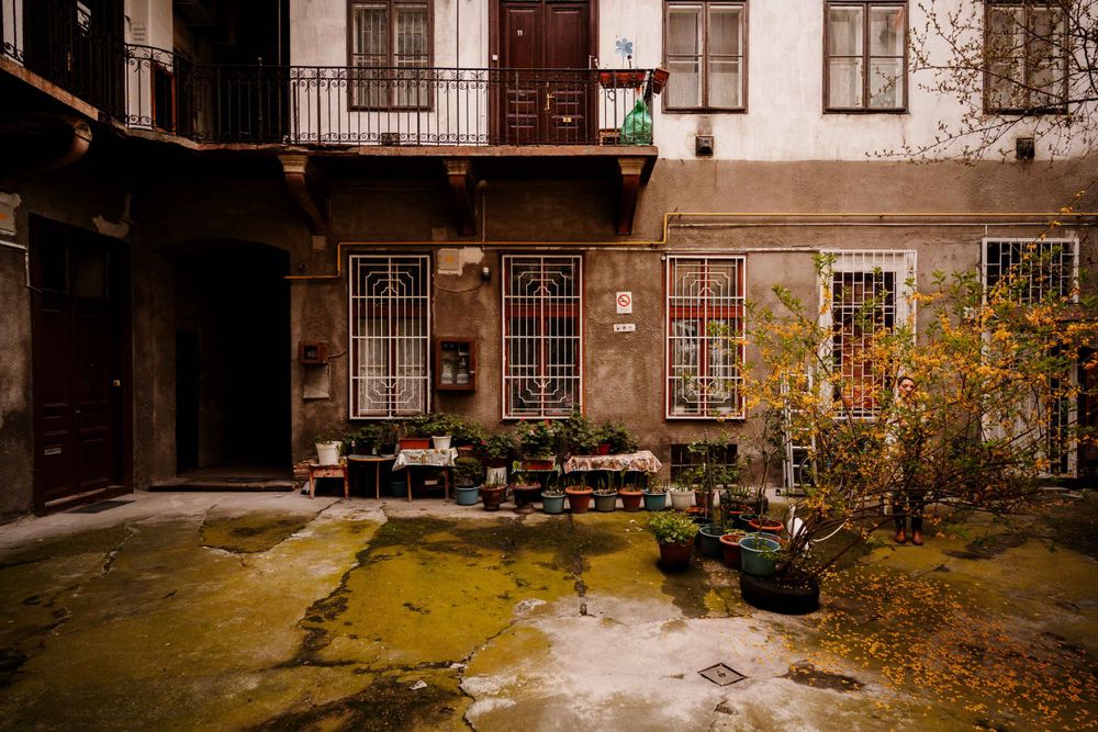 Historic courtyard with balconies and potted plants in an old European apartment building.