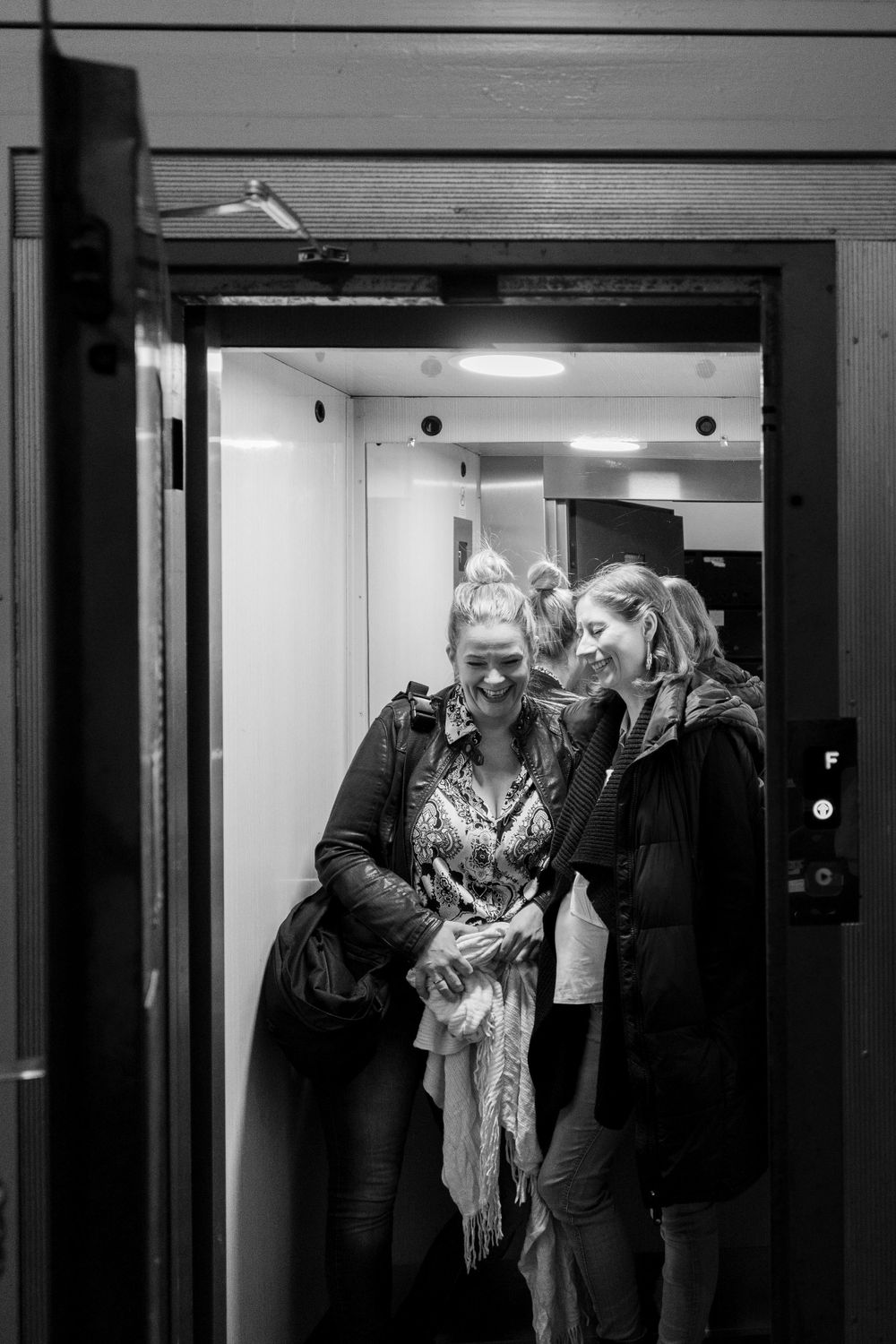 Two people sharing a moment while standing in a brightly lit elevator.
