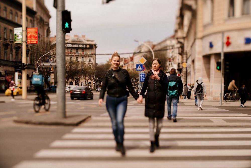 Friends crossing urban street intersection with historic buildings in background.