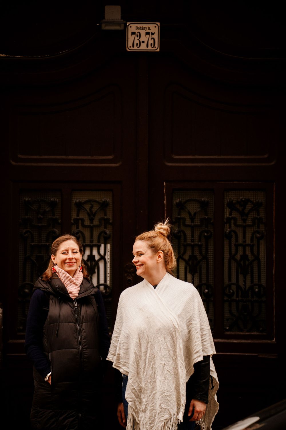 Two people sharing a lighthearted moment in front of an ornate wooden door.