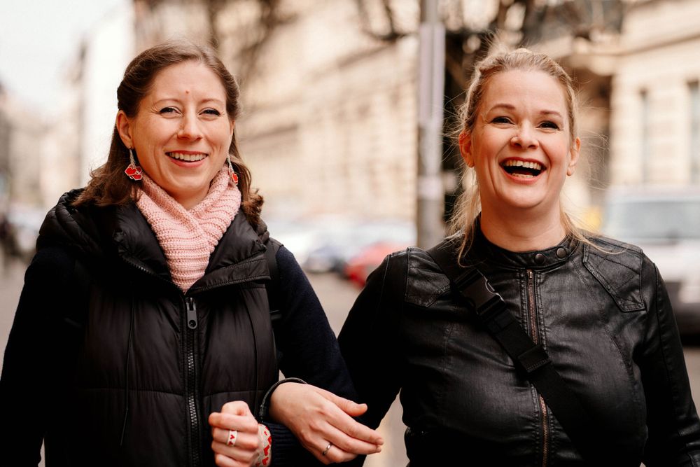 Two friends sharing a joyful moment while walking on a winter city street.