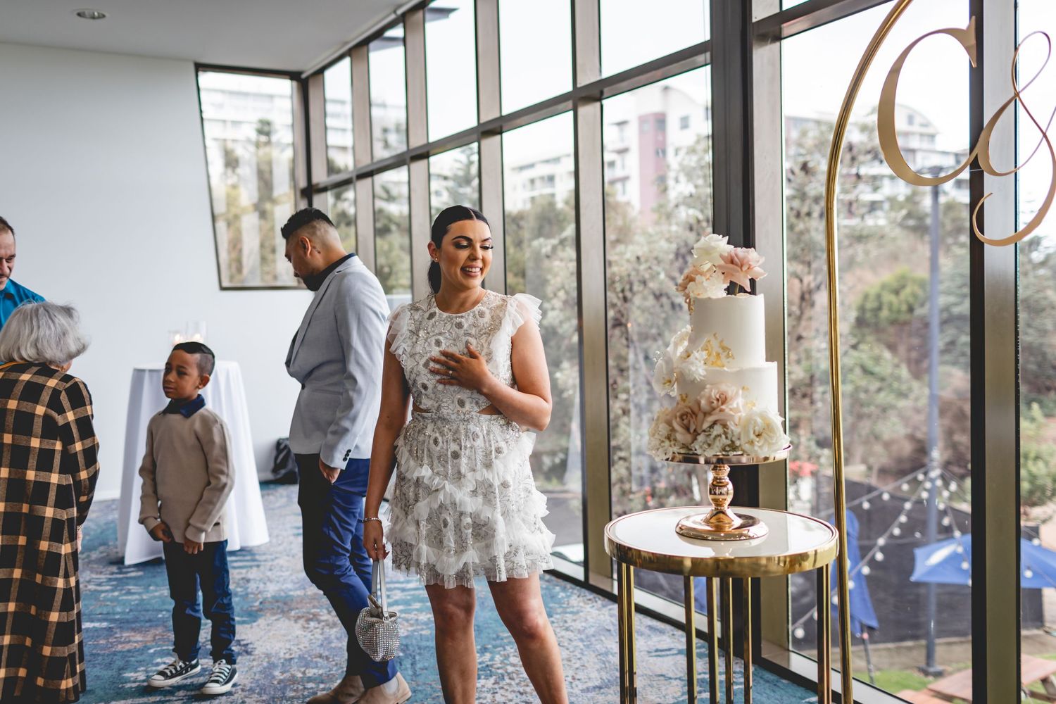 Modern wedding venue with floor-to-ceiling windows and elegant cake display.