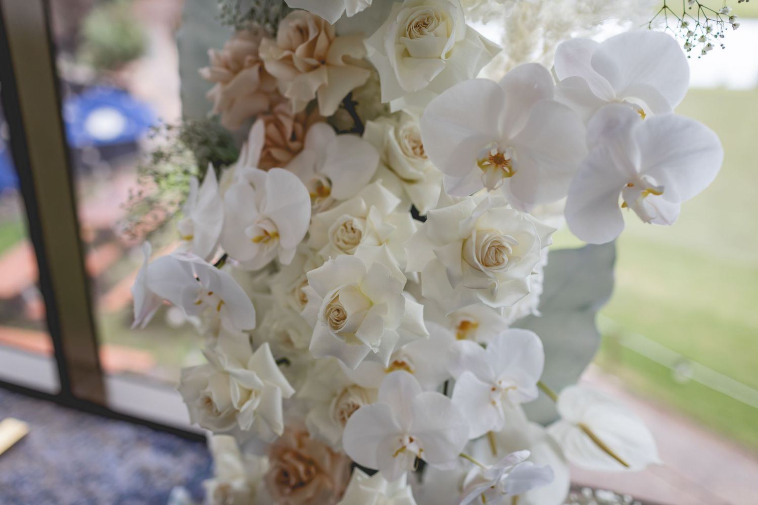 Close-up of luxurious white orchids and roses arranged in an elegant wedding arch display.