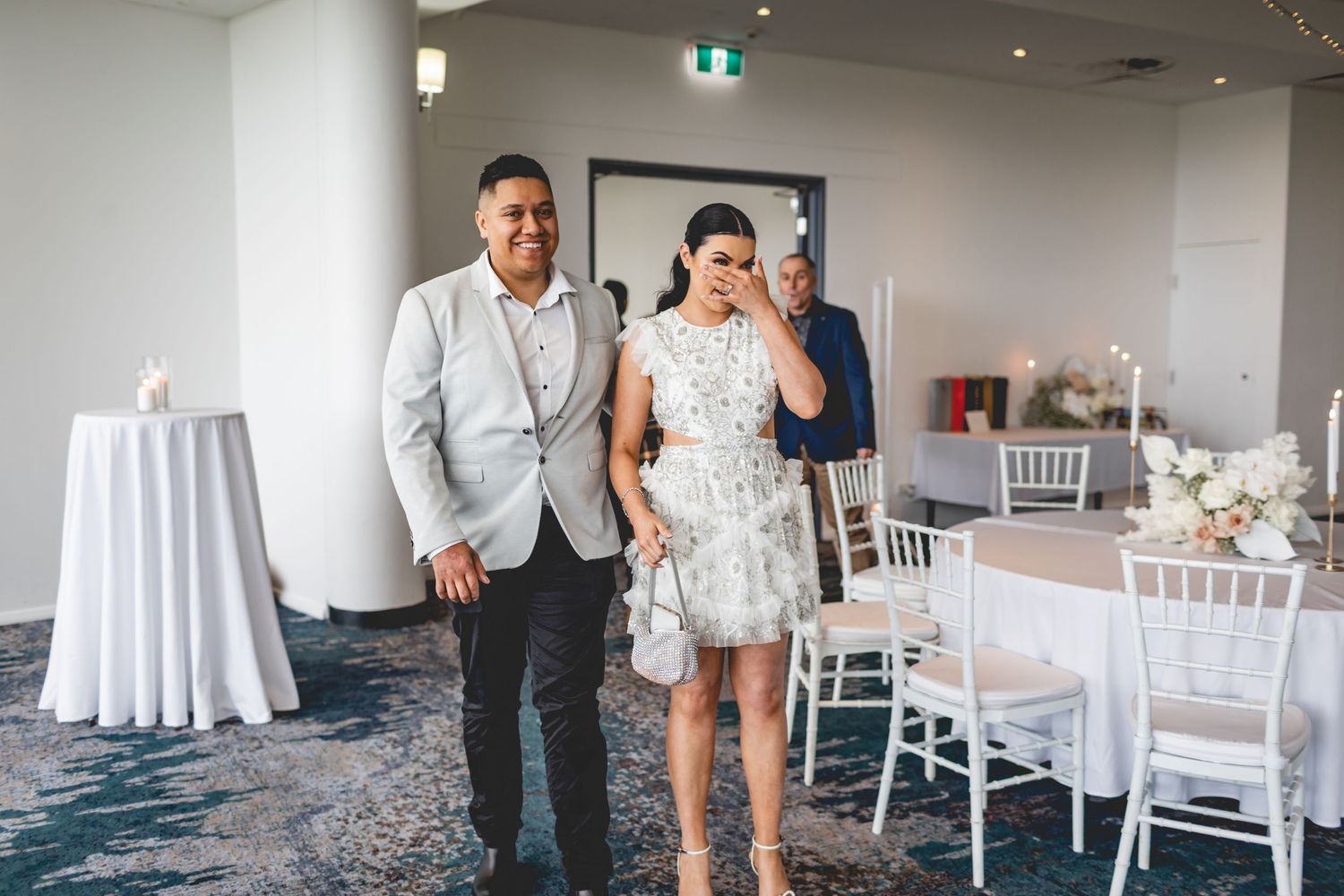 Wedding celebration in modern venue with blue carpet and white table settings.