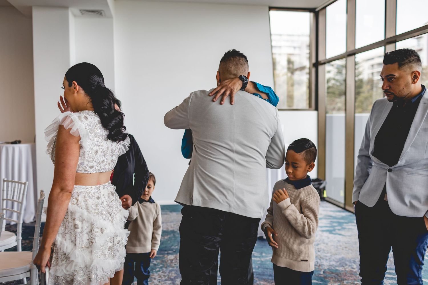 Wedding guests gather in modern reception venue with blue carpeted floors.