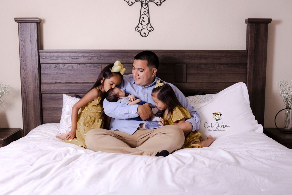 Loving family cuddle together on bed with matching outfits and decorative wall art.