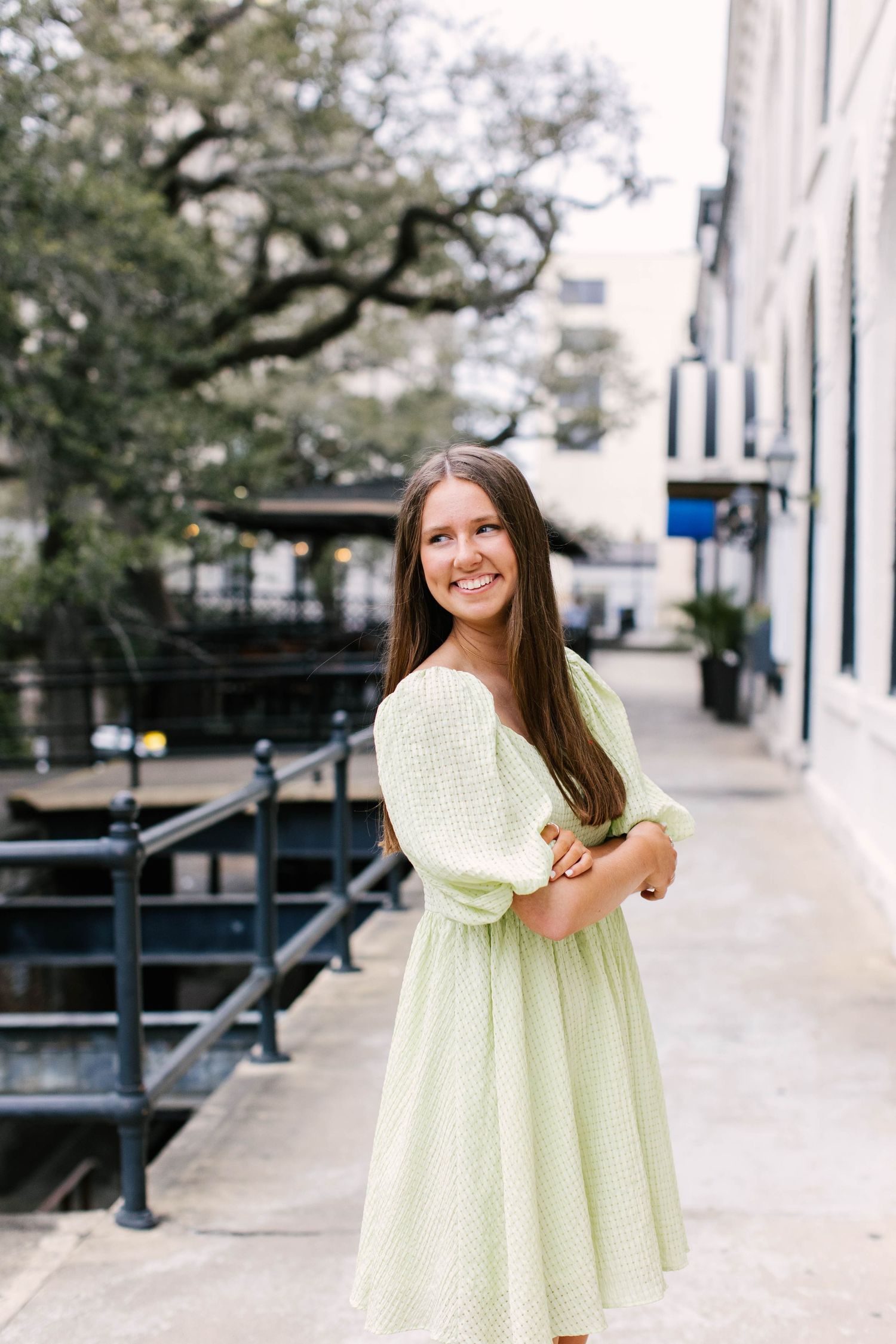 Portrait of woman in pale green dress against historic building backdrop.
