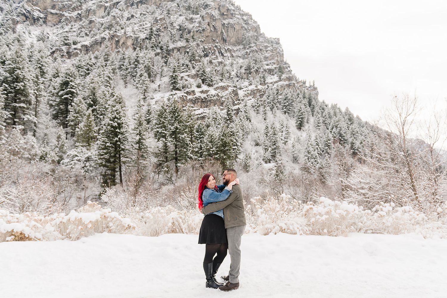 A romantic embrace captured in a snow-covered mountain landscape.