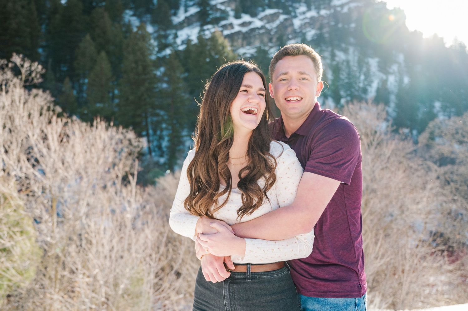 A couple sharing a joyful moment together against a wintry mountain backdrop.