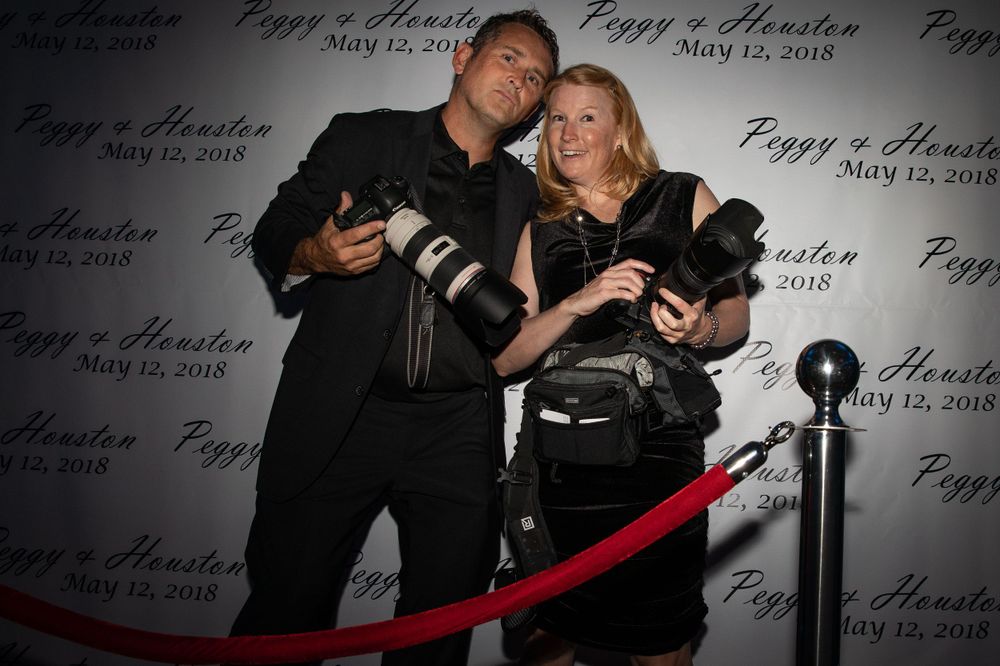 Event photographers pose with cameras at formal red carpet event.