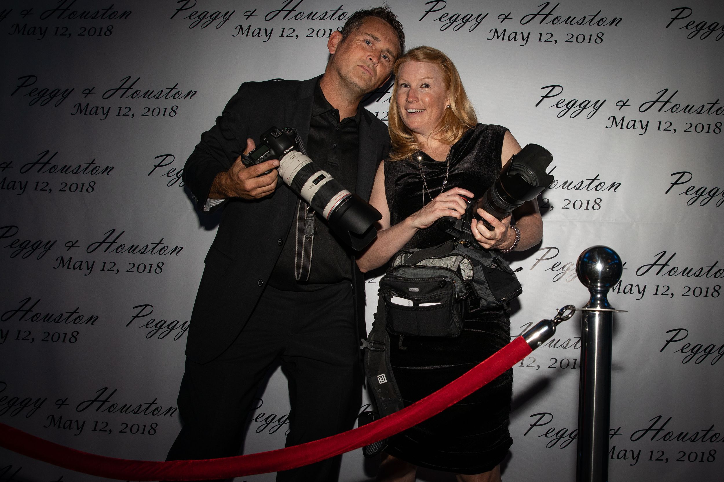 Event photographers pose with cameras at formal red carpet event.