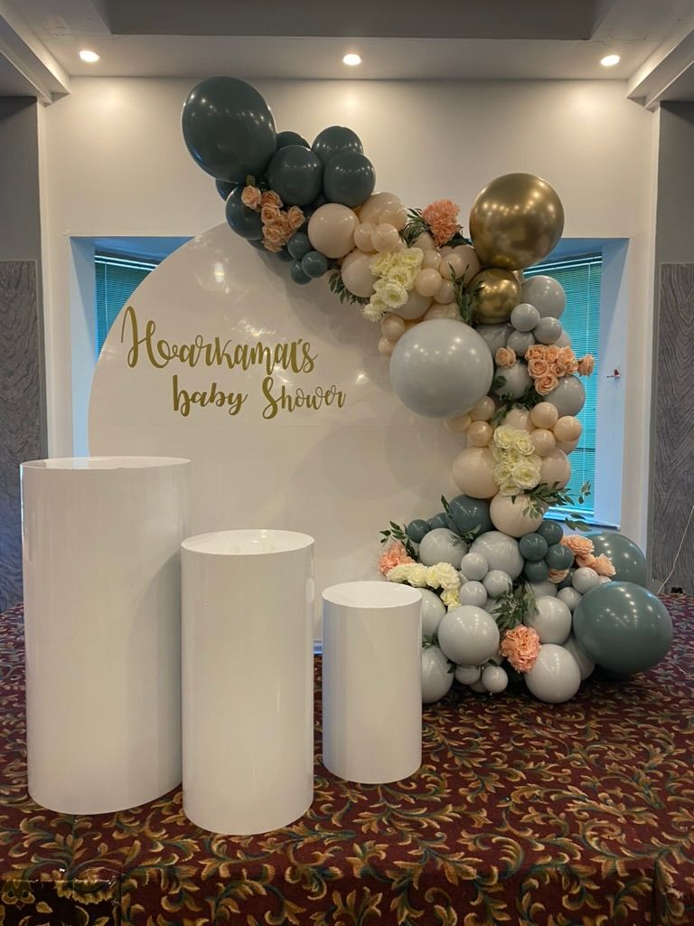 Baby shower theme decor - White acrylic round backdrop, sage green and bush balloons and florals, three dessert plinths