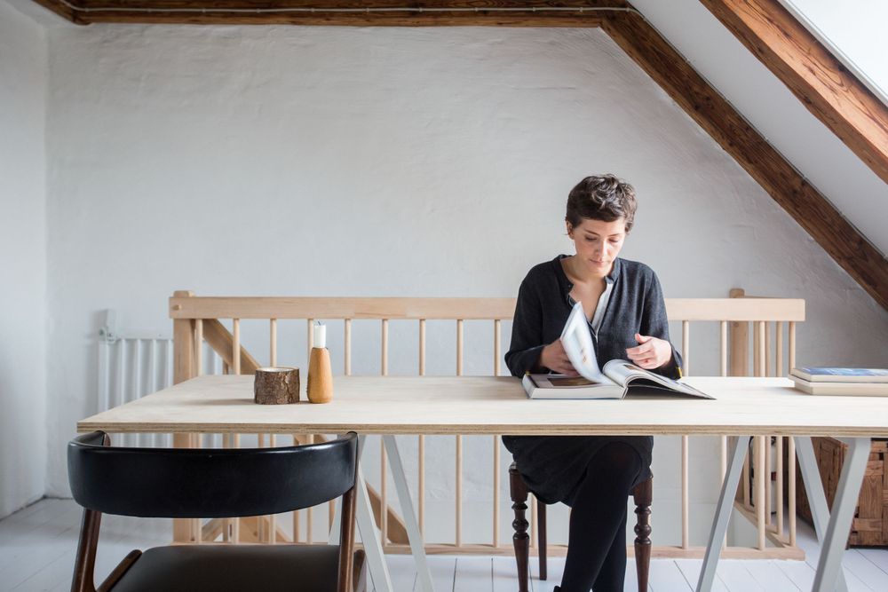 Woman sitting at a table in a Scandinavian interior in a house reading a book