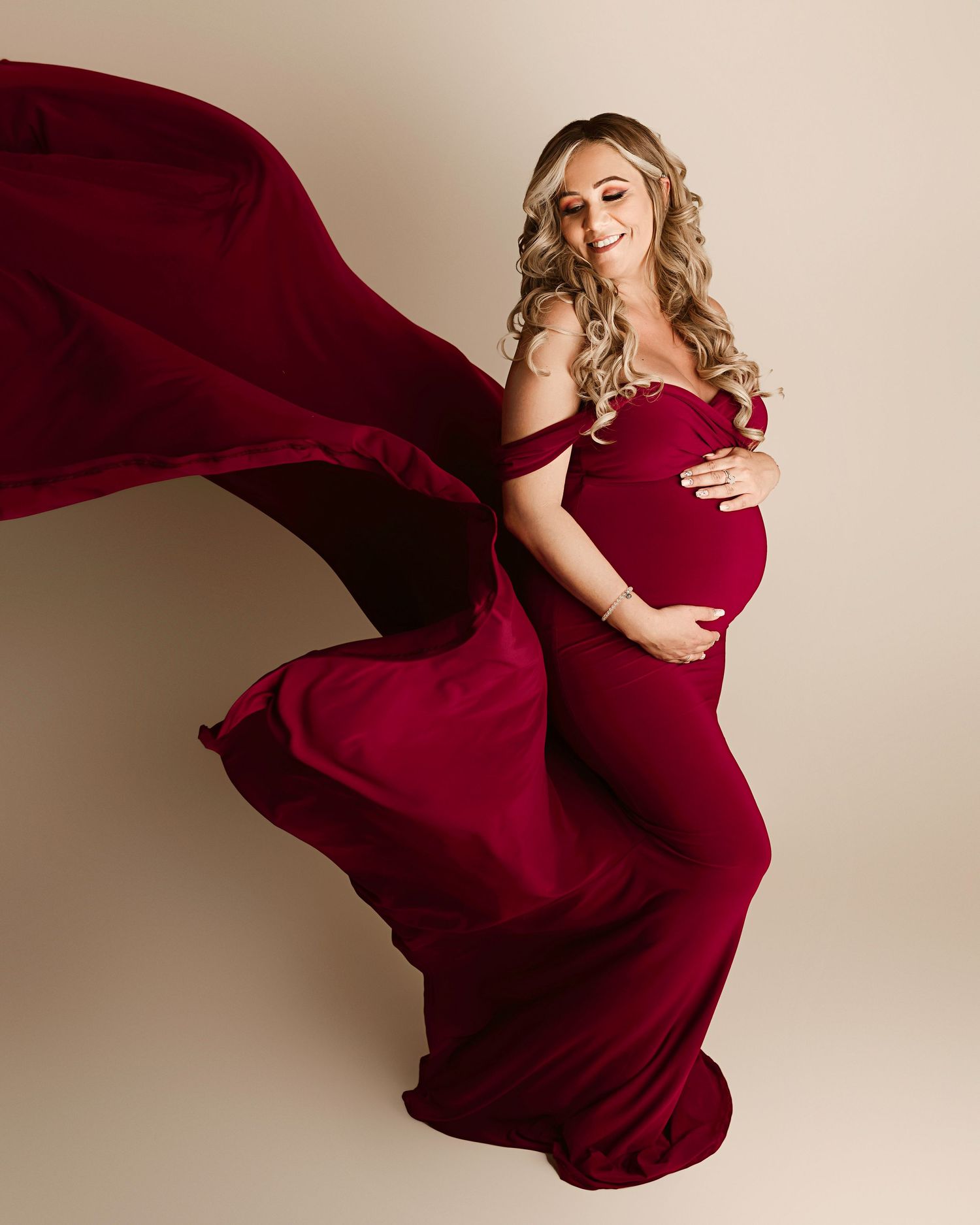 Riverside maternity photographer, woman looking over shoulder with fabric toss