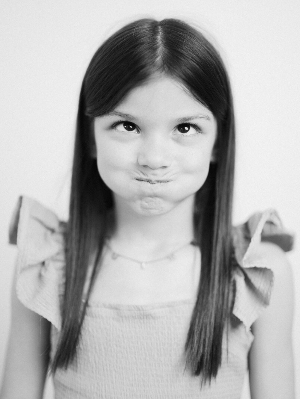 Black and white portrait series showing playful facial expressions and long straight dark hair.