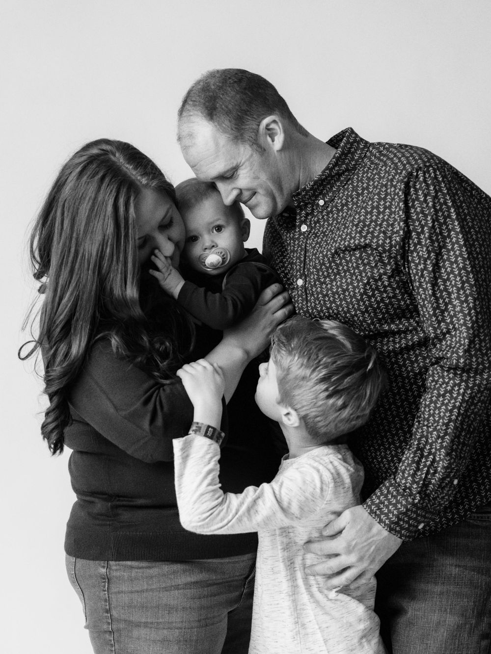 Intimate black and white family portrait series showing tender moments of embrace.