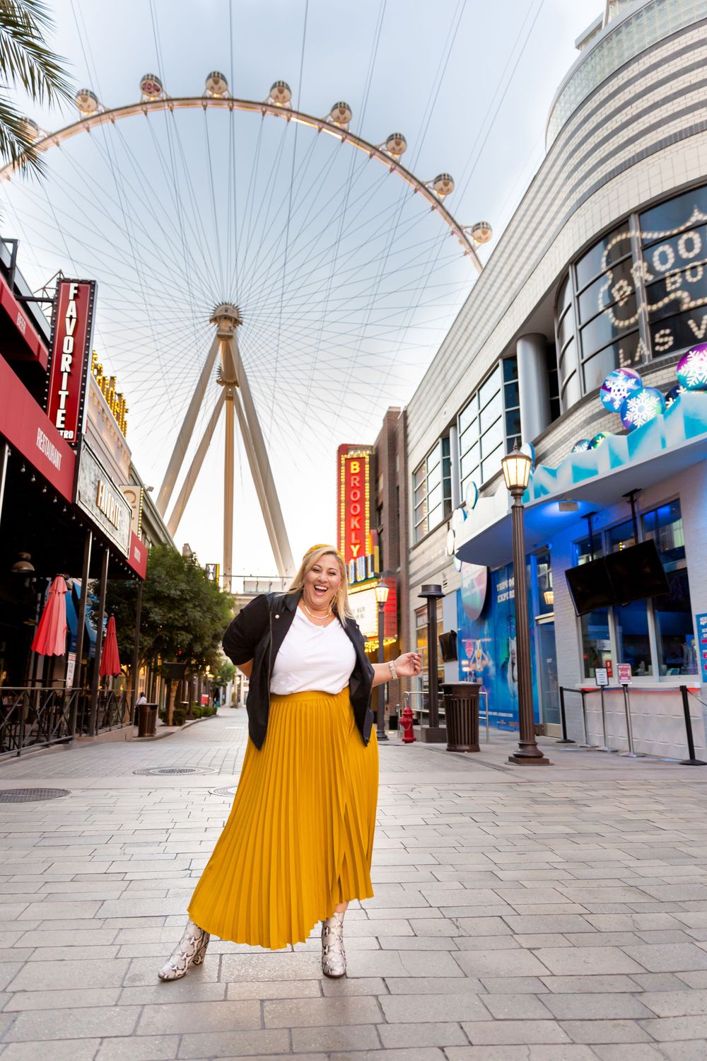 Striking fashion pose in yellow pleated skirt with High Roller observation wheel in background.