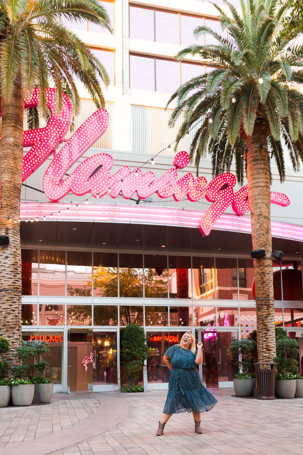 Dancing in front of the iconic pink Flamingo Las Vegas sign surrounded by palm trees.