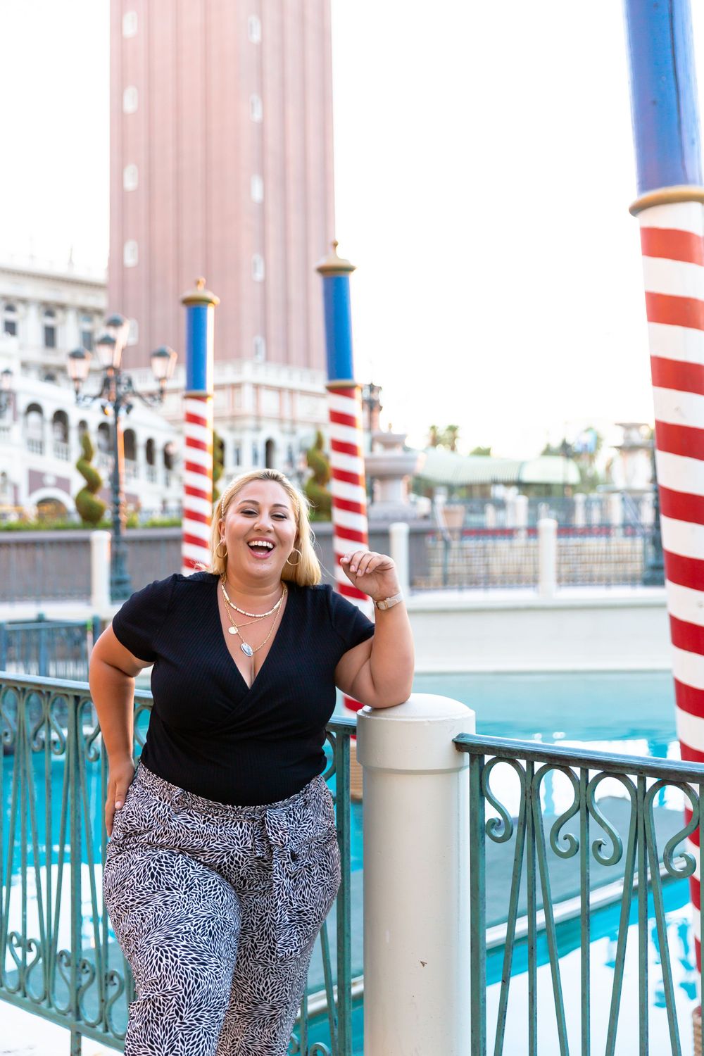 Energetic pose between red and blue striped poles at Venetian resort.
