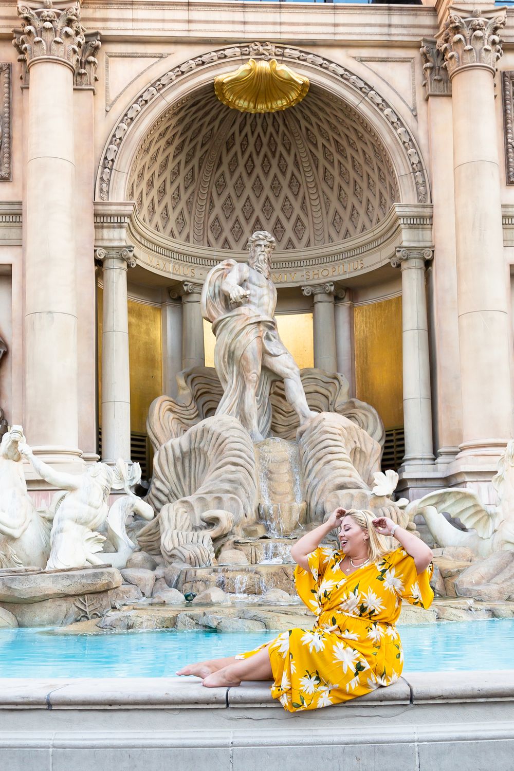 Elegant yellow dress contrasts beautifully against the historic Trevi Fountain's baroque architecture and blue water.