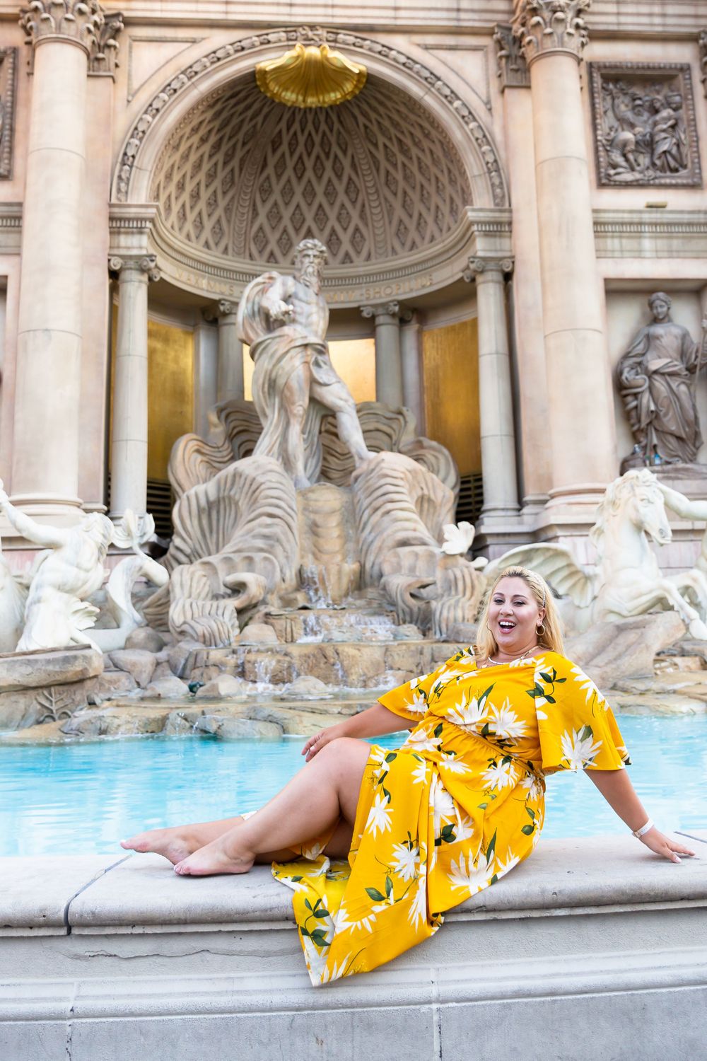 Yellow floral dress worn by visitor at the iconic Trevi Fountain in Rome with classical architecture backdrop.