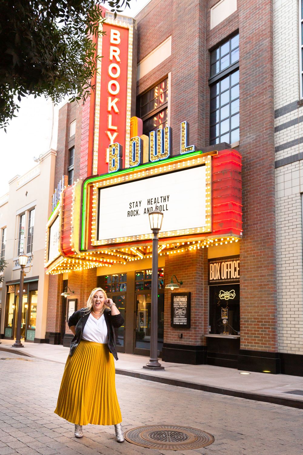 Yellow skirt twirling in front of the Brooklyn Theater with its classic vintage marquee and brick facade.