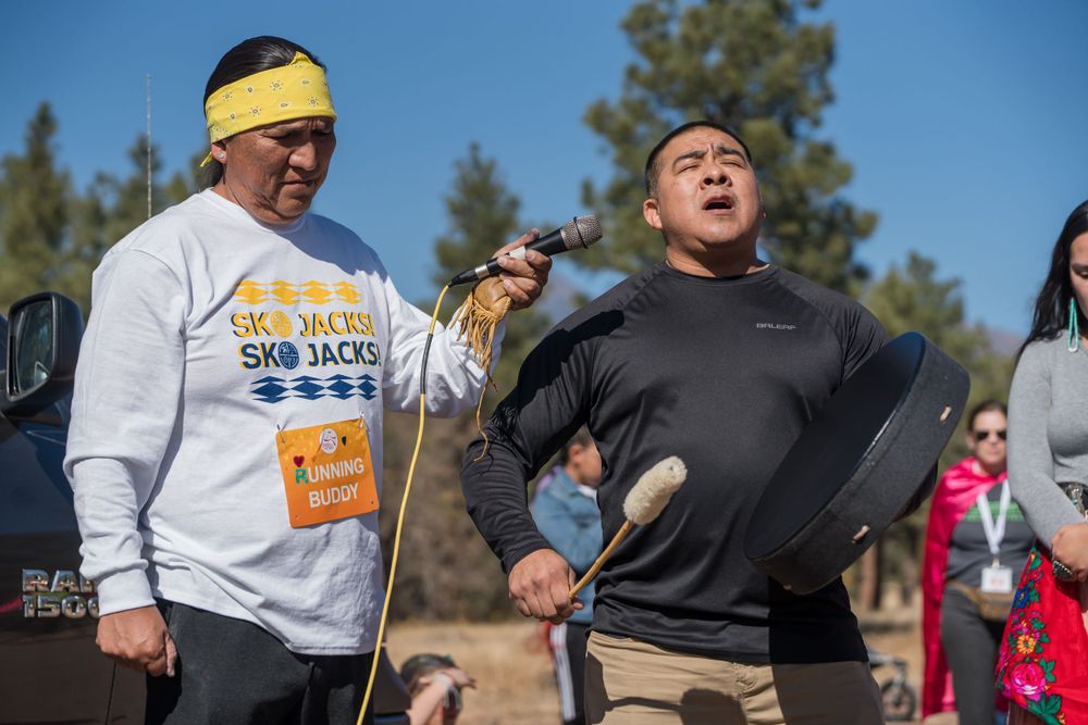 Runners showing enthusiasm during outdoor race event with mountains in background.