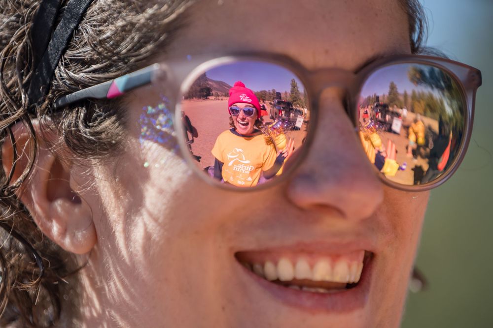 Reflections of colorful crowd visible in sunglasses at outdoor event.