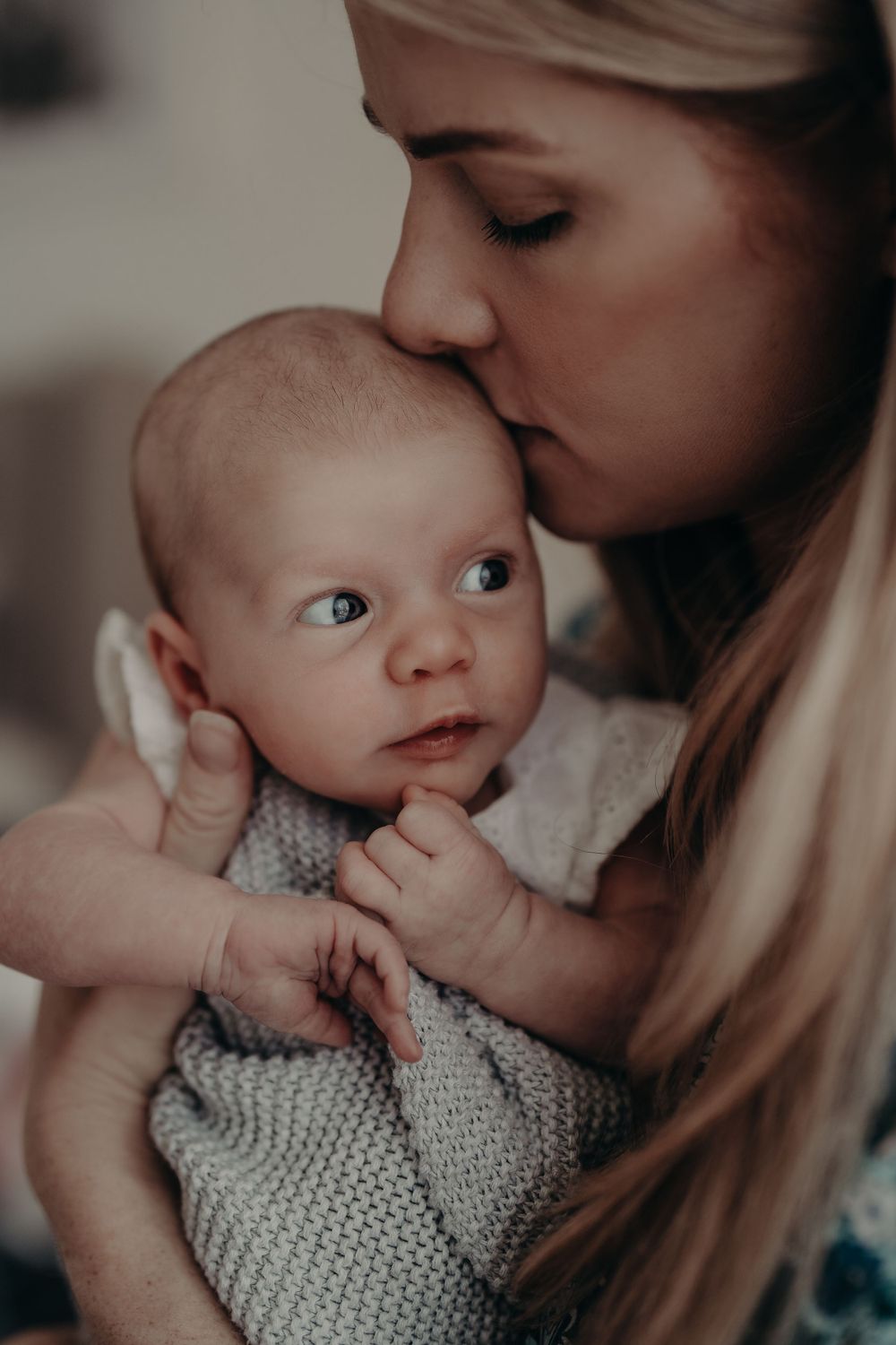 A tender moment captured as someone kisses a baby's head while holding them close.