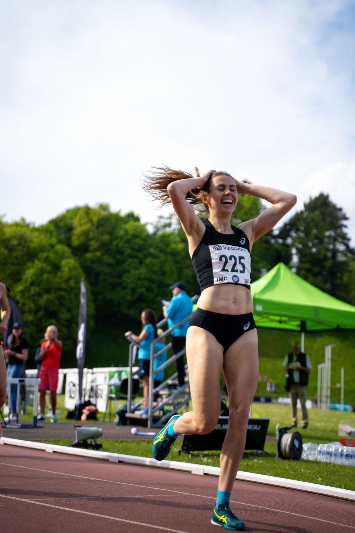 Athletic runner celebrating with joy during an outdoor track competition.