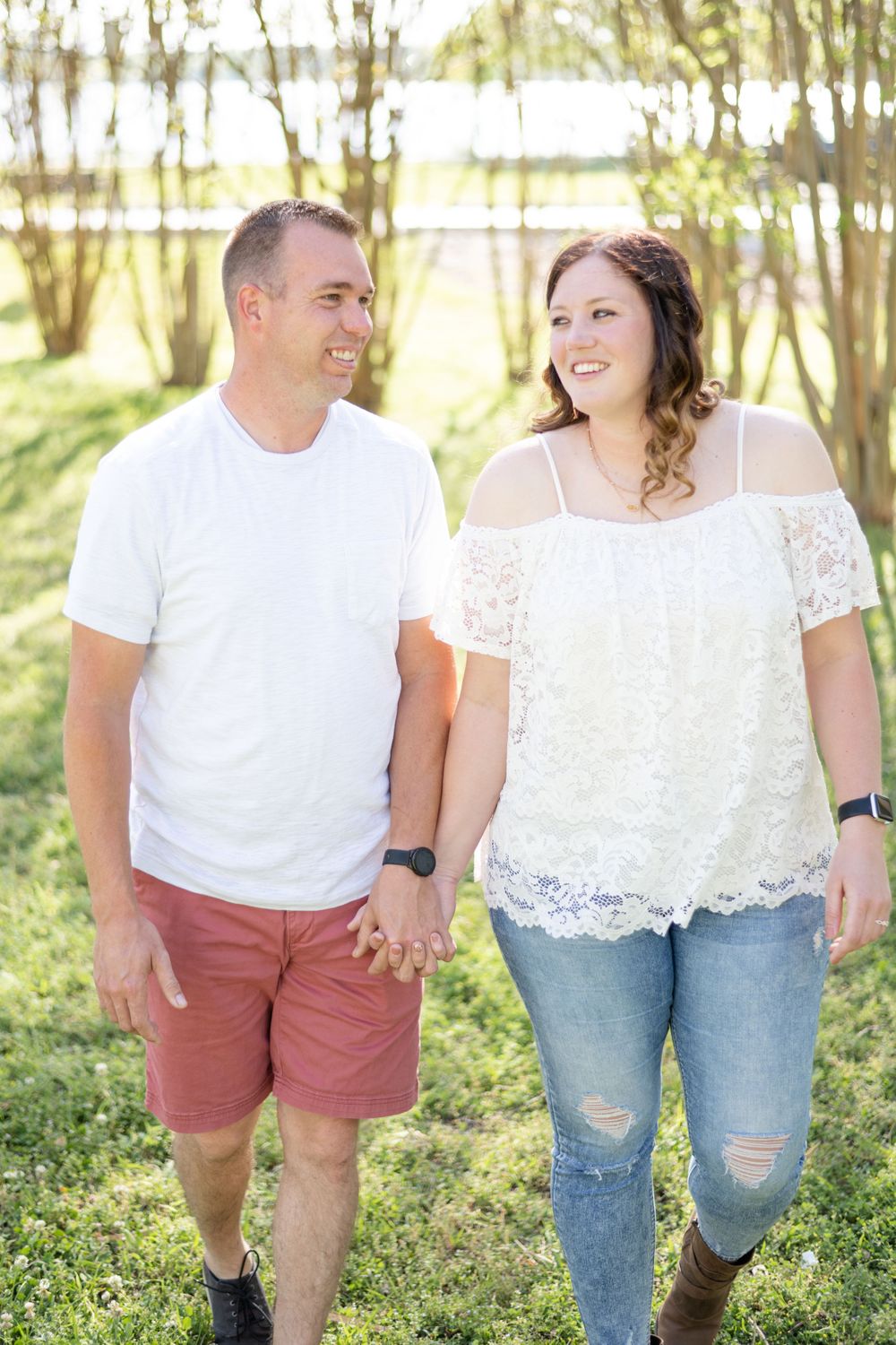 A couple in casual spring outfits holding hands while walking outdoors.
