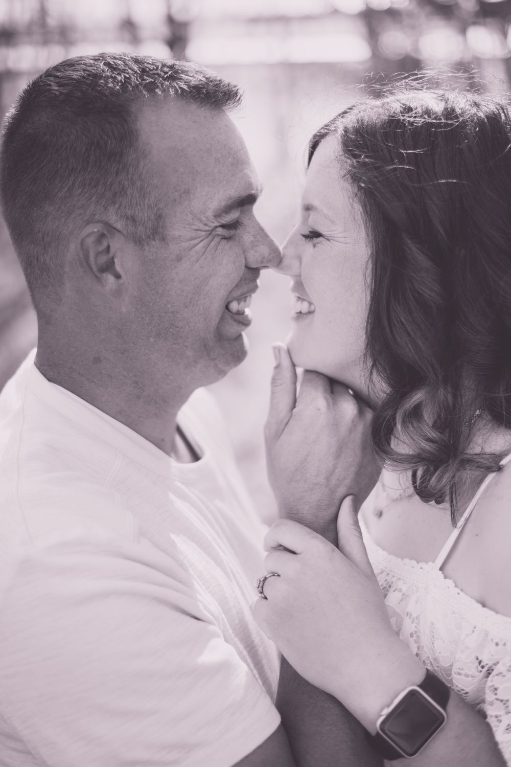 An intimate black and white portrait of a couple about to kiss.